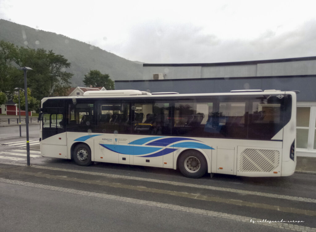 Autobús viajando por carretera entre montañas noruegas