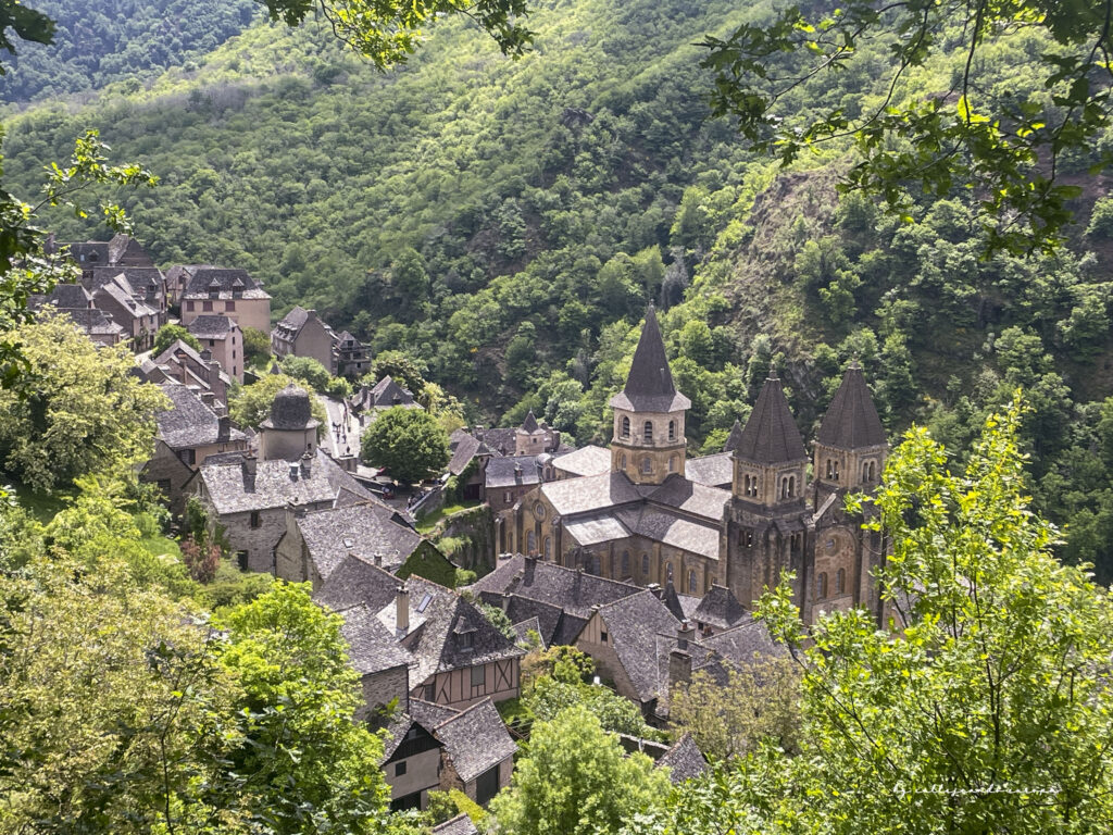 Casas medievales y la abadía de Conques entre colinas verdes