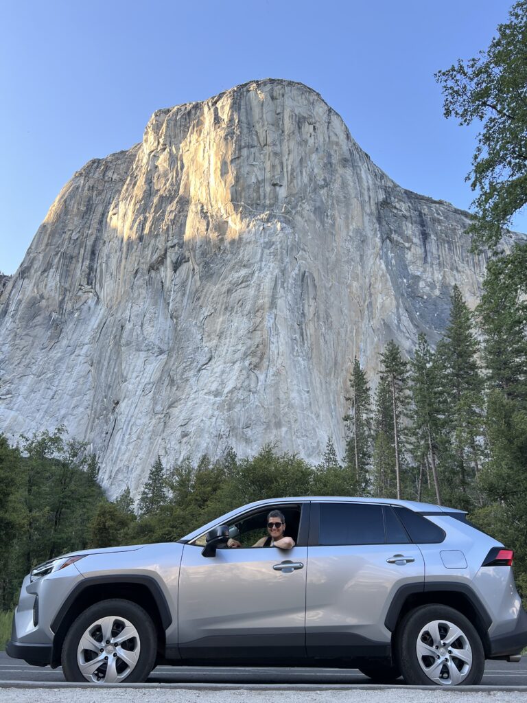Coche de alquiler aparcado frente a El Capitán en el Parque Nacional de Yosemite, perfecto para recorrer la Costa Oeste de Estados Unidos por libre