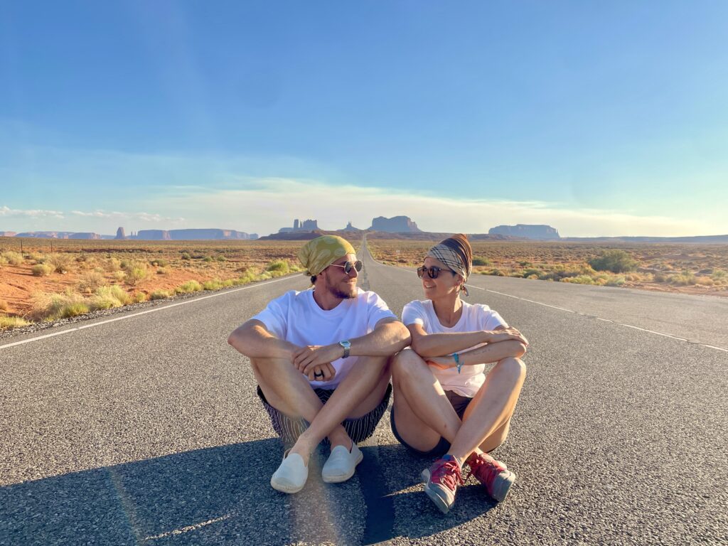 Sentados en la carretera del punto Forrest Gump en Monument Valley durante ruta por el Oeste de Estados Unidos con Callejeando Europa