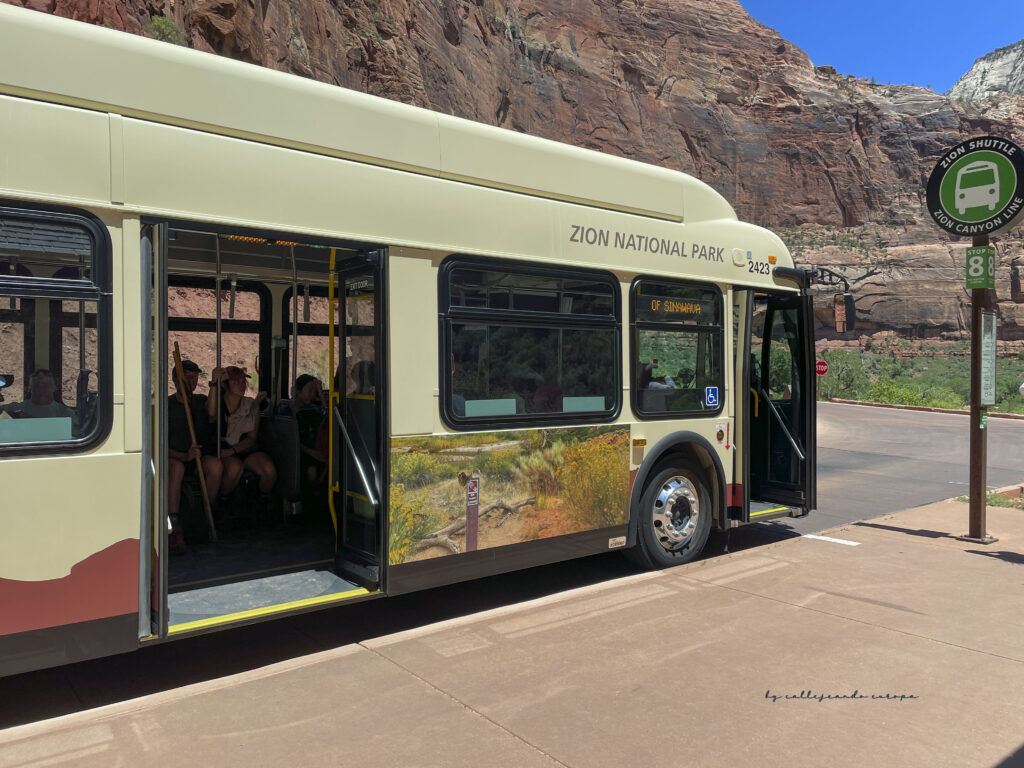 Shuttle bus del Parque Nacional Zion recorriendo el cañón entre montañas de roca roja