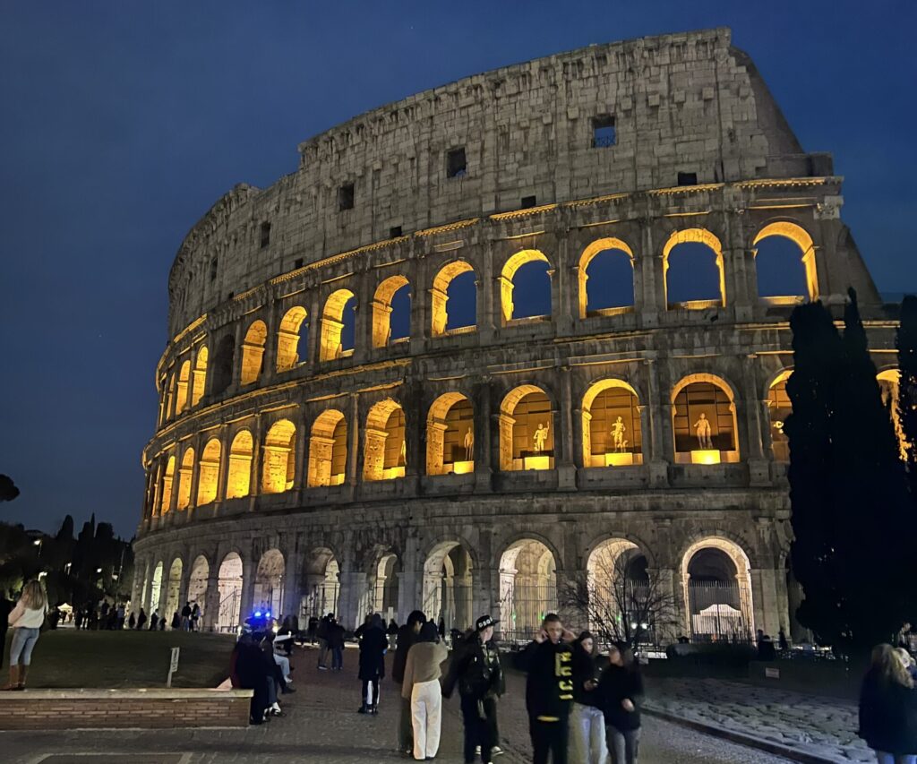 El Coliseo Romano iluminado por la noche bajo un cielo estrellado, una de las mejores vistas nocturnas que visitar en Roma.