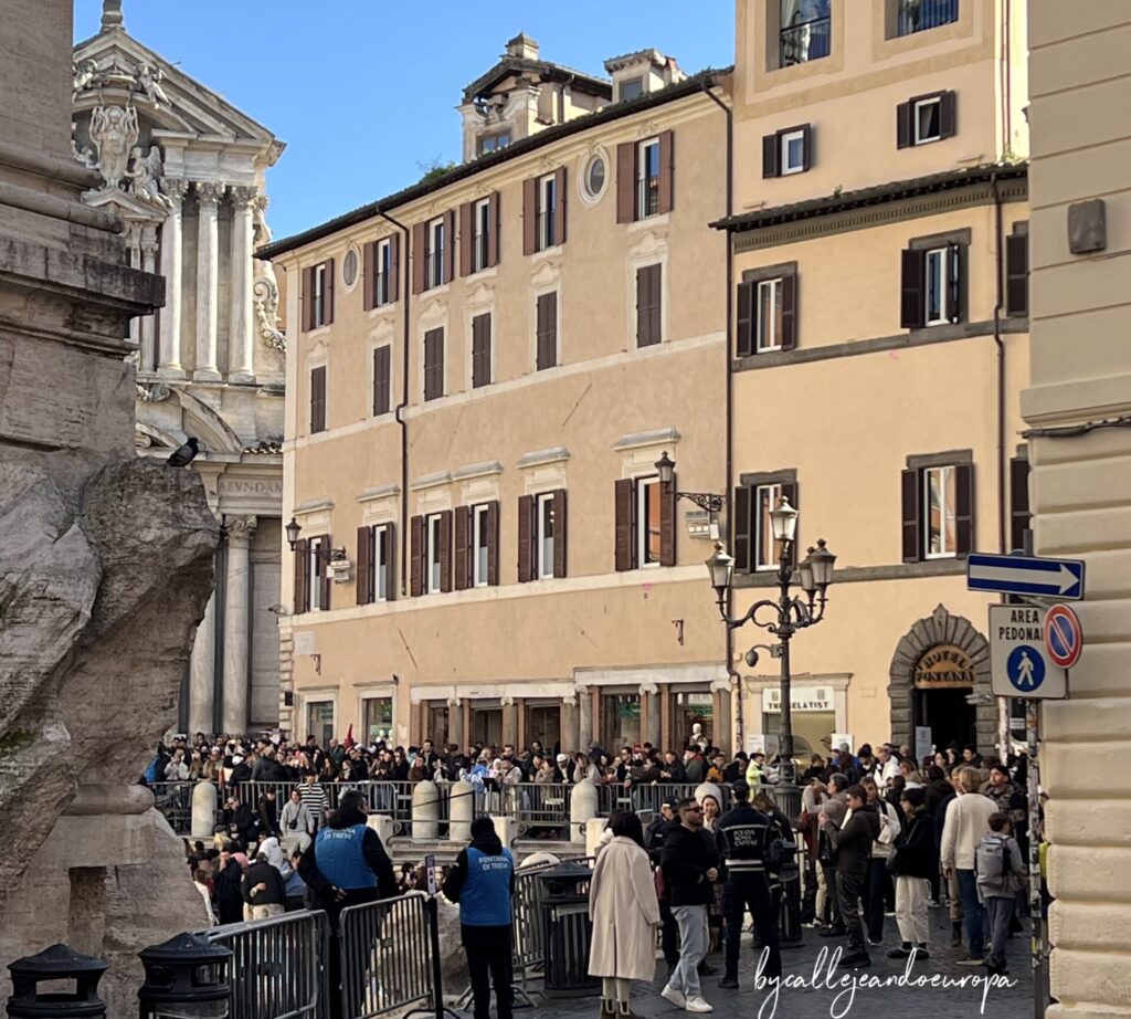 Gran cantidad de visitantes esperando para acceder a la orilla de la Fontana de Trevi en un día soleado en Roma.