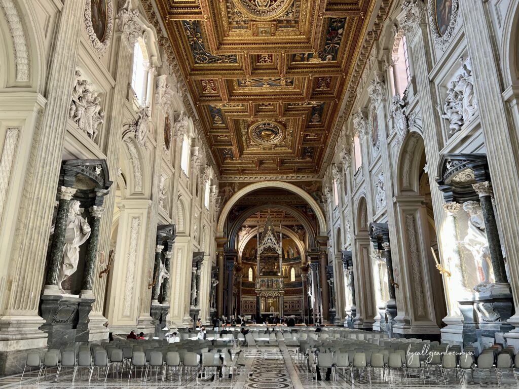 Interior de la Archibasílica de San Juan de Letrán en Roma, mostrando su techo artesonado dorado, estatuas de los apóstoles y el altar mayor