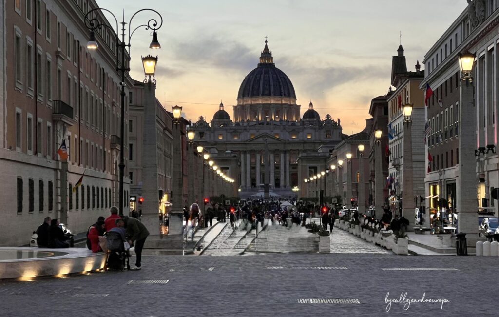 Vista panorámica de la Via della Conciliazione al atardecer con la Basílica de San Pedro al fondo iluminada, Ciudad del Vaticano.
