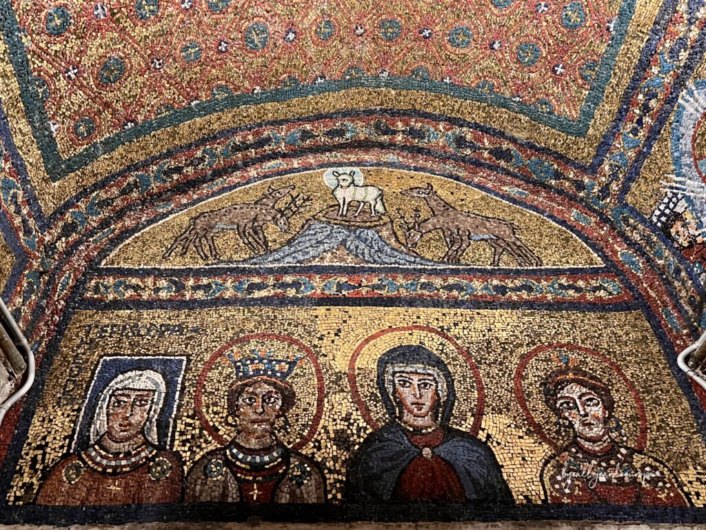 Mosaico de la Capilla de San Zenón en la Basílica de Santa Práxedes que muestra el Cordero del Apocalipsis sobre una colina con ciervos bebiendo, y debajo las figuras de las Santas Teodora, Inés, Práxedes y Pudenciana