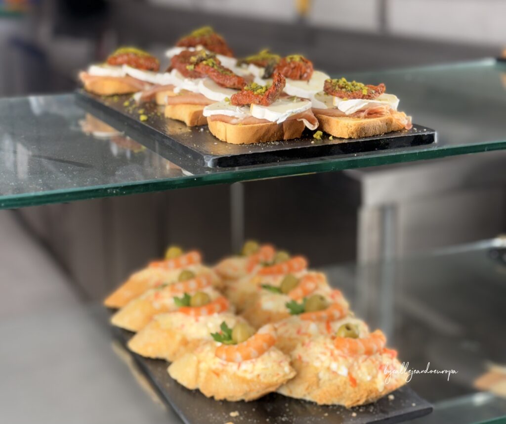 Barra de pintxos en San Sebastián: montaditos de jamón con tomate seco y ensaladilla con gambas
