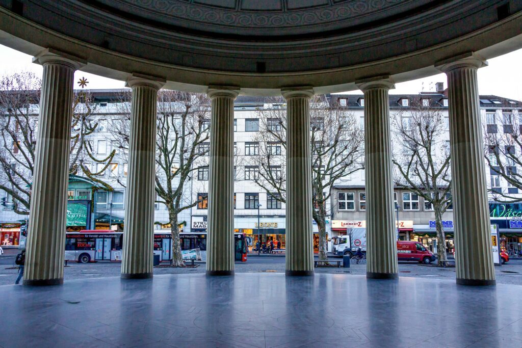 Neoclassical columns framing a street view in Aachen, Germany with winter scenery.