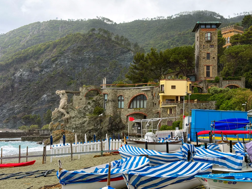 La famosa estatua de piedra Il Gigante en la playa de Fegina con barcas de pescadores en Monterosso al Mare, Cinque Terre