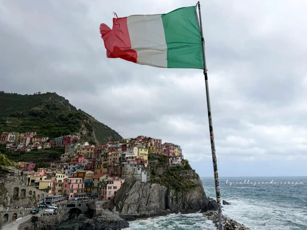 Vistas del pueblo de Manarola en Cinque Terre con la bandera de Italia en primer plano