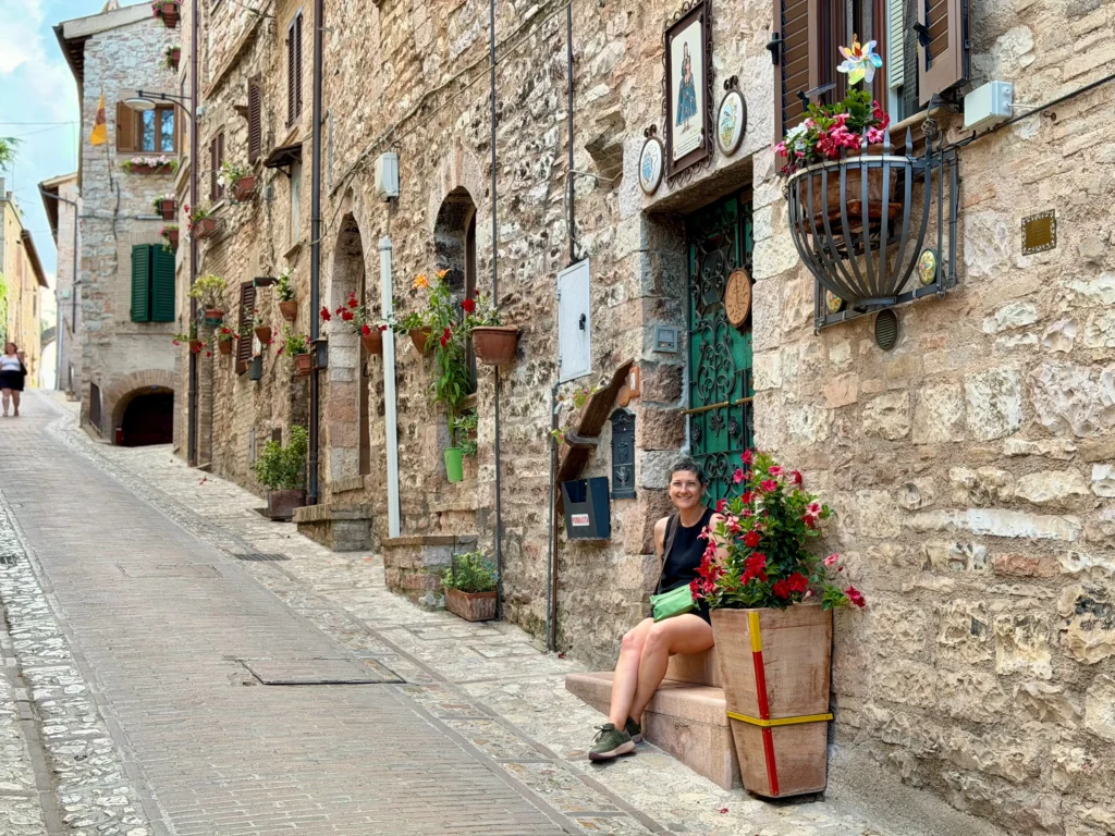 Calle con fachadas de piedra y flores en el casco histórico de Spello, Umbría