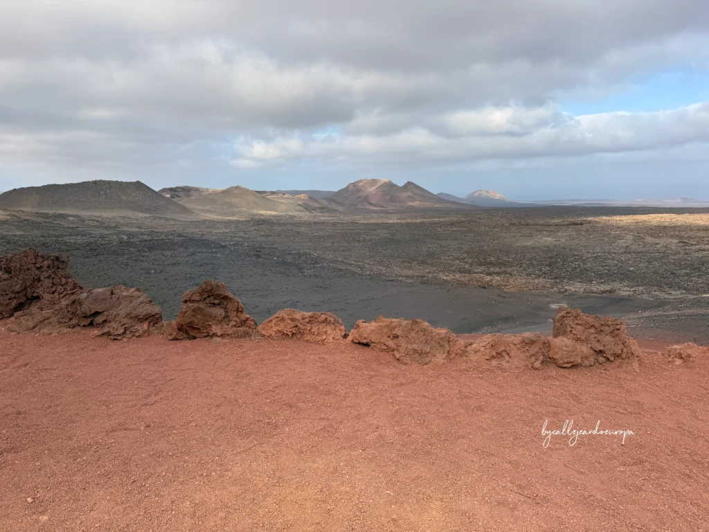 Paisaje volcánico de las Montañas del Fuego con tierra roja y campos de lava negra en Timanfaya, Lanzarote, Islas Canarias